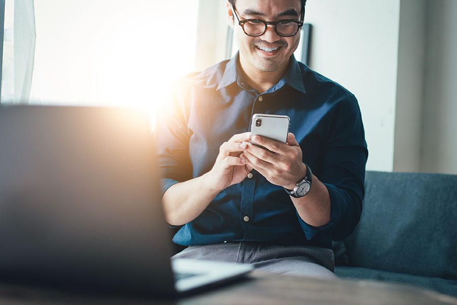 Report a Claim - Man Sitting on Sofa Using His Phone